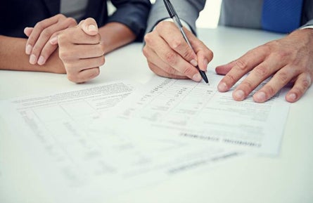 Two people filling a form on a white table