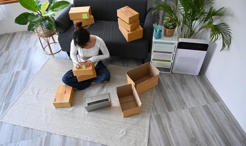 Young woman sitting on the floor an tagging moving boxes