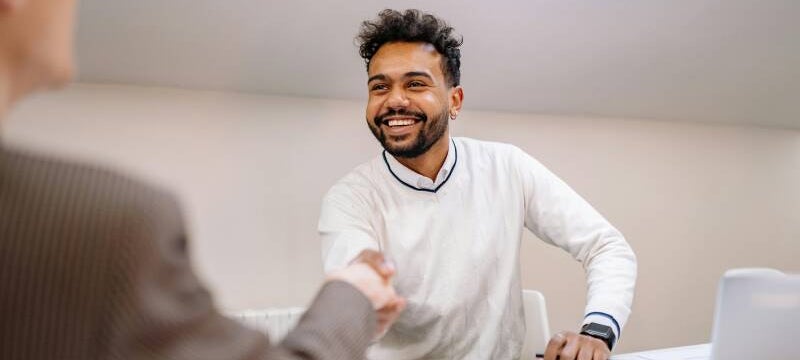 Young man smiling and shaking the interviewers hand in a job interview