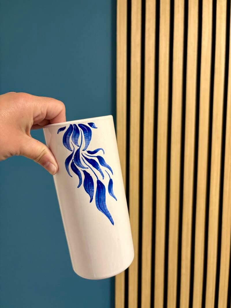 Een witte vaas van de kringloop geupcycled. Met porseleinstiften in blauw een decoratie erop getekend in bladermotief.