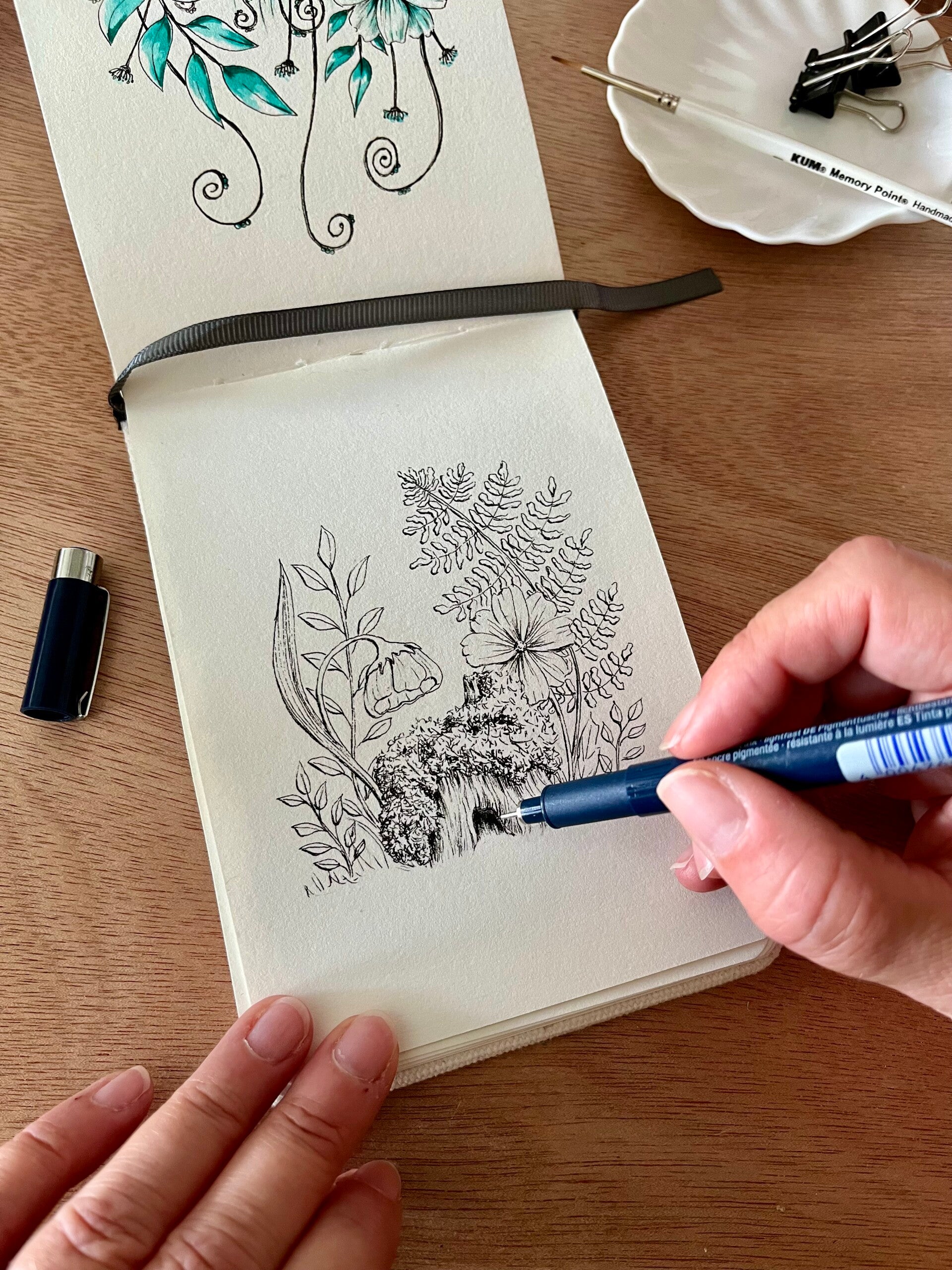 Een pentekening in zwart van een een bostafereel met mos , bloemen en en varen.