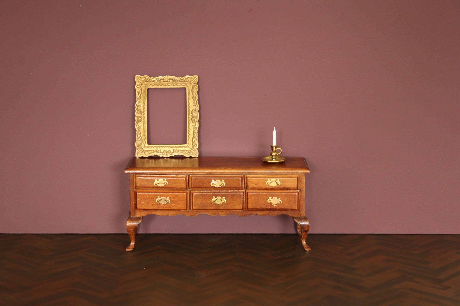 Houten ladekast met elegante poten en goudkleurige handgrepen.