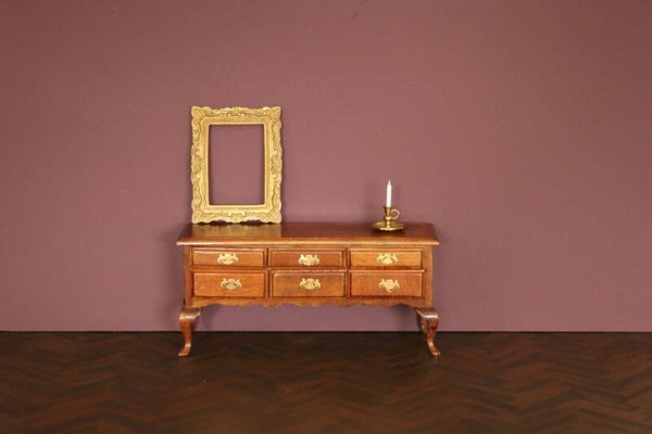 Houten ladekast met elegante poten en goudkleurige handgrepen.