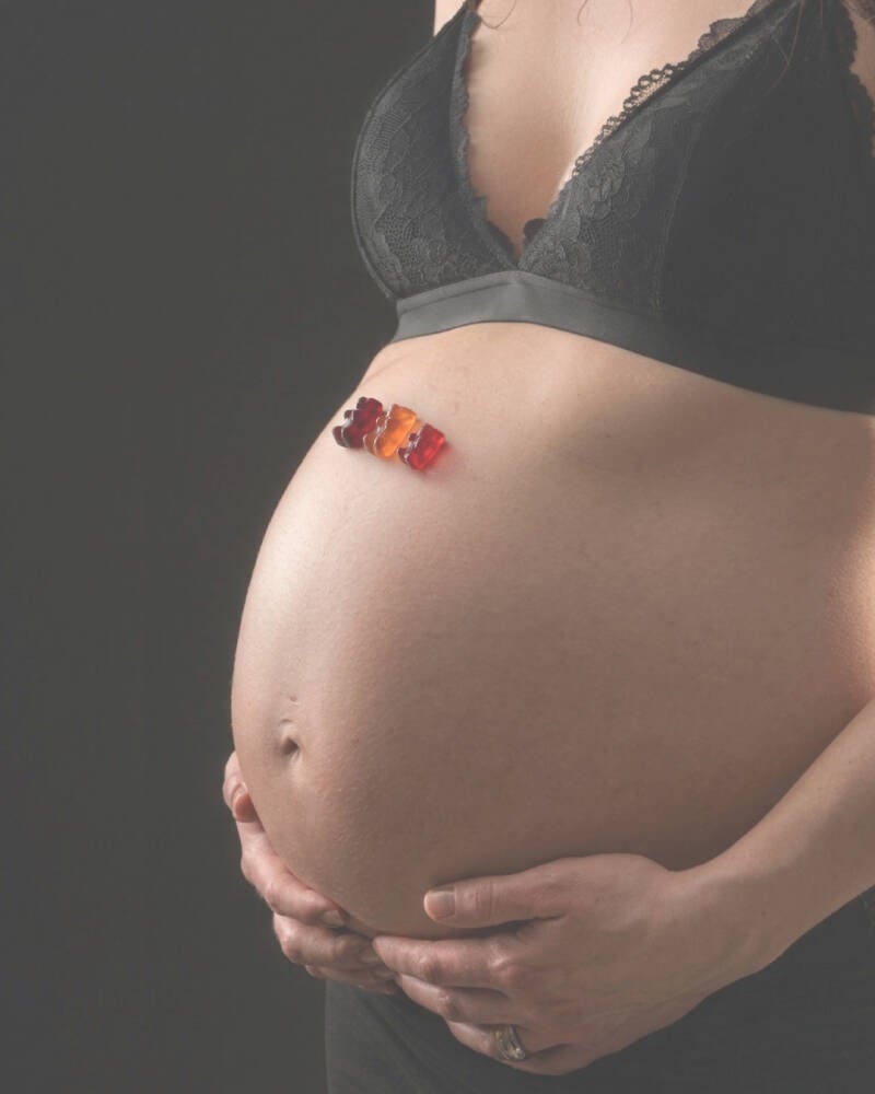 Babybauch Shooting mit drei Gummibärchen als Symbol für die wachsende Familie – kreative, persönliche Schwangerschaftsfotografie.