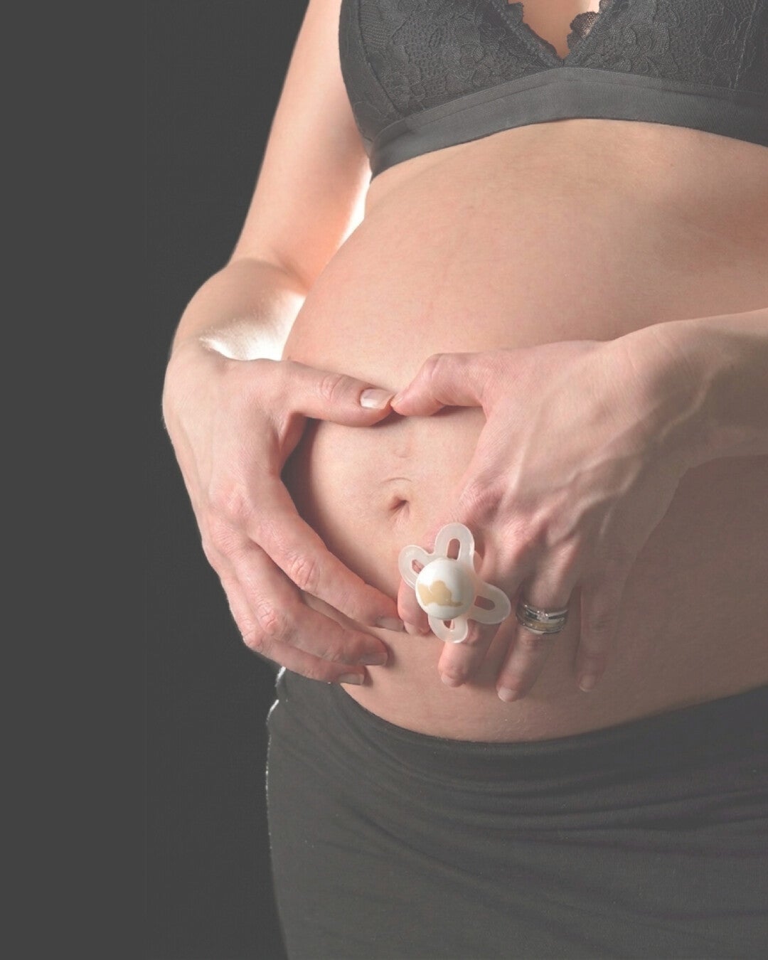 Babybauch Foto mit Schnuller – emotionales Schwangerschaftsshooting mit liebevollen Details.