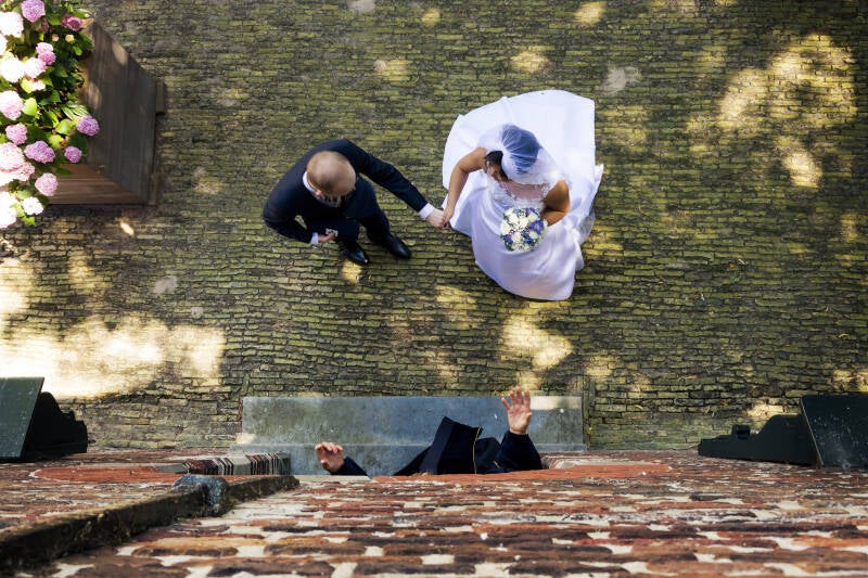bruidspaar vanaf boven te zien terwijl de trouwambtenaar ze naar binnen in de trouwzaal begeleid