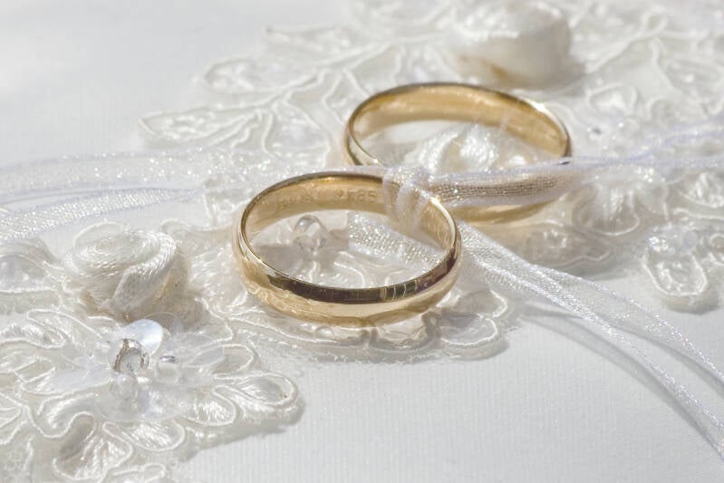 twee trouwringen liggend op een wit kanten kussen