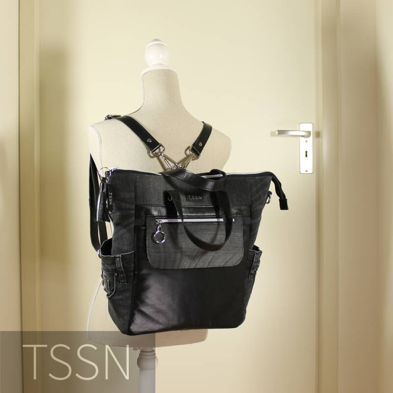 De tas als rugtas van zwarte spijkerbroek en oud leren bankstel op paspop