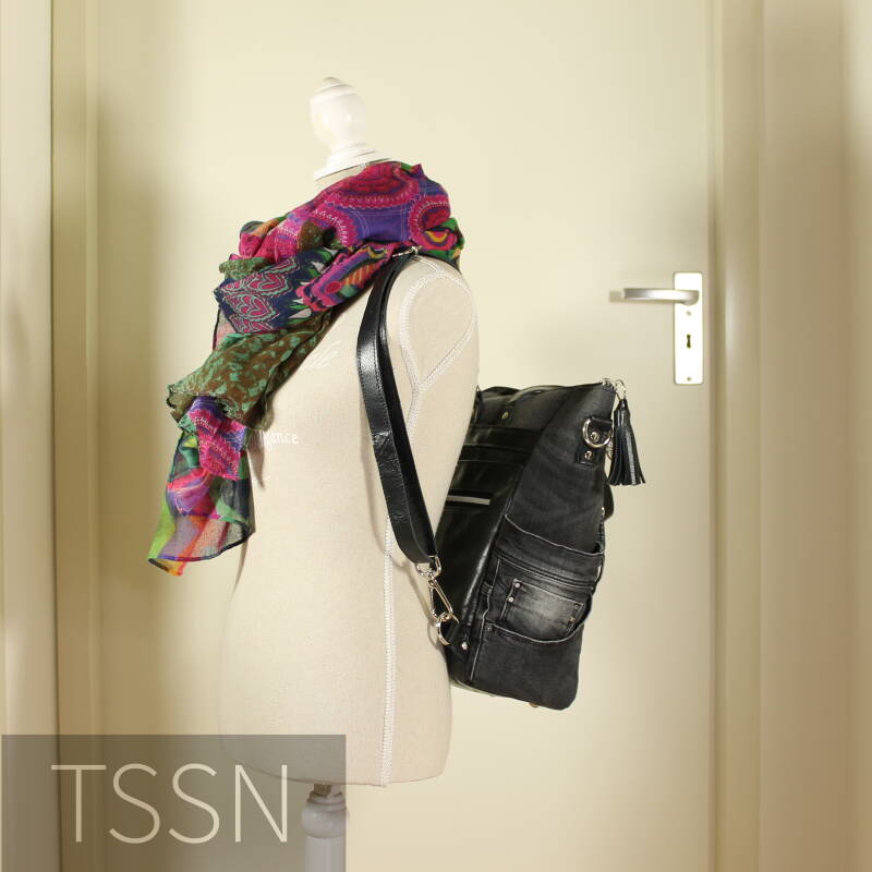 De tas als rugtas van zwarte spijkerbroek en oud leren bankstel op paspop