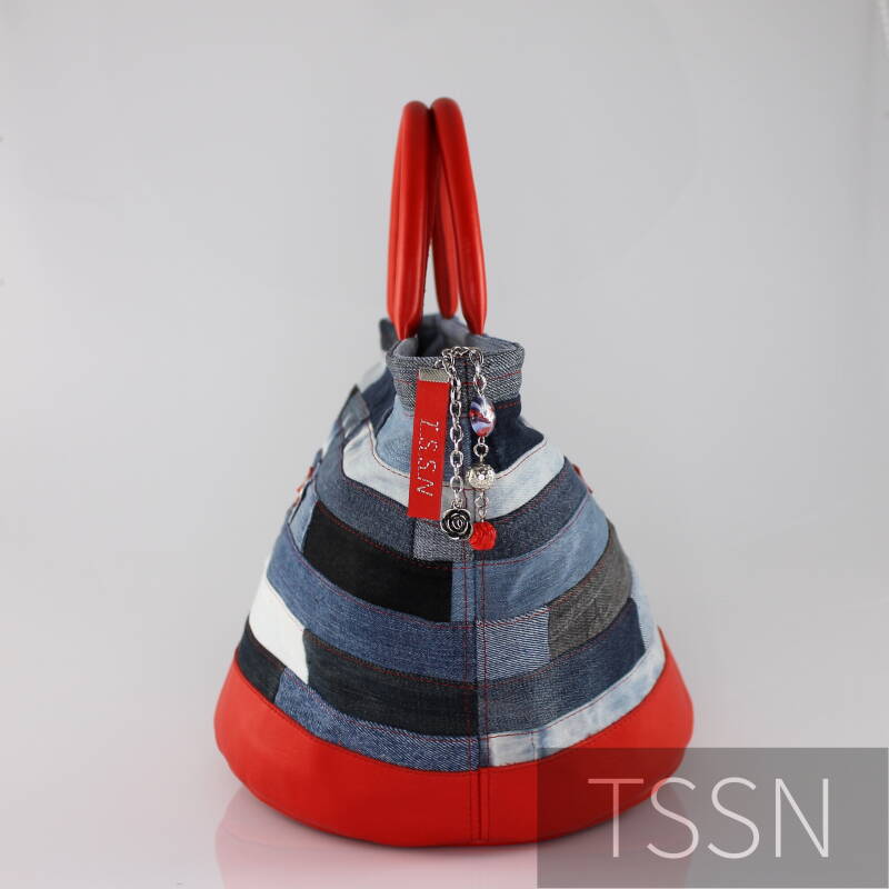 Zijkant Bucket bag model Esther 2 gemaakt van meerdere kleuren denim stroken en rood leer