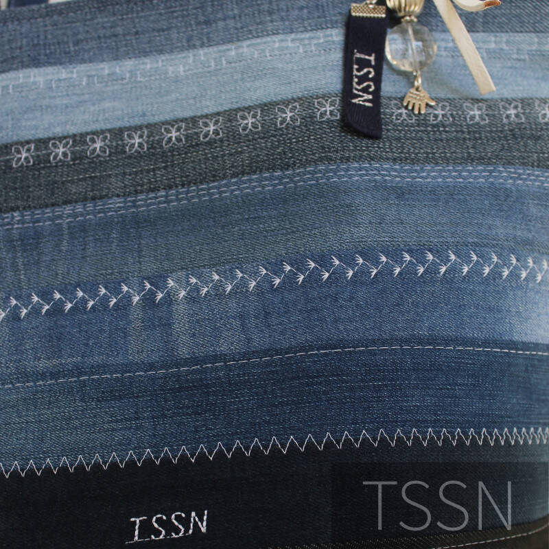 Detailfoto van bucketbag model Esther van meerdere verschillend gekleurde spijkerbroeken.