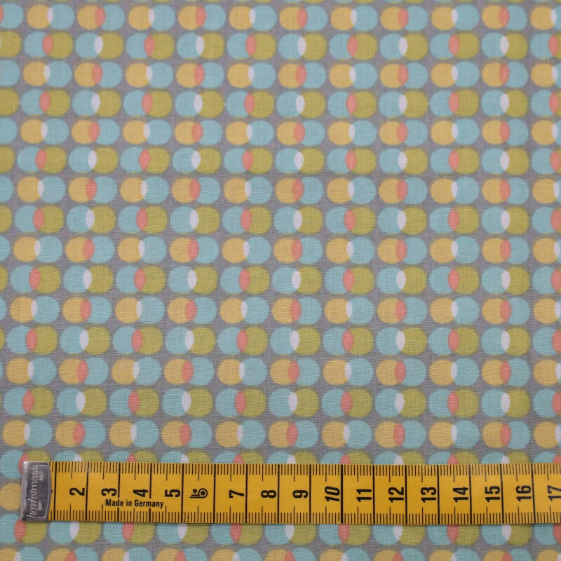 grijze ondergrond met balletjes in lichtblauw, geel, oranje en groen