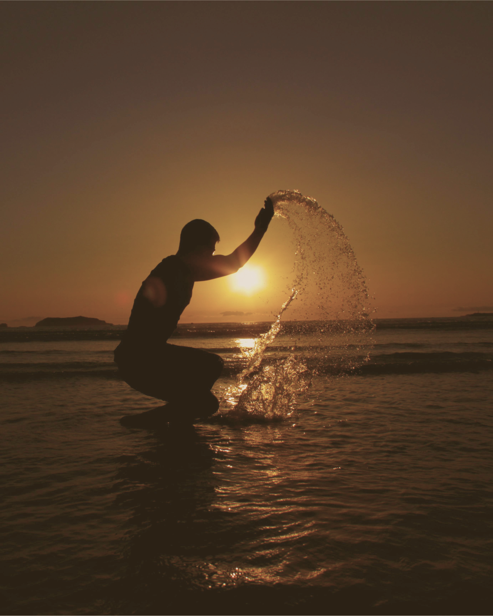 Silhouette lançant de l’eau dans la lumière du couchant, symbole du programme ÉVOLUTION et du passage du feu à la vie.
