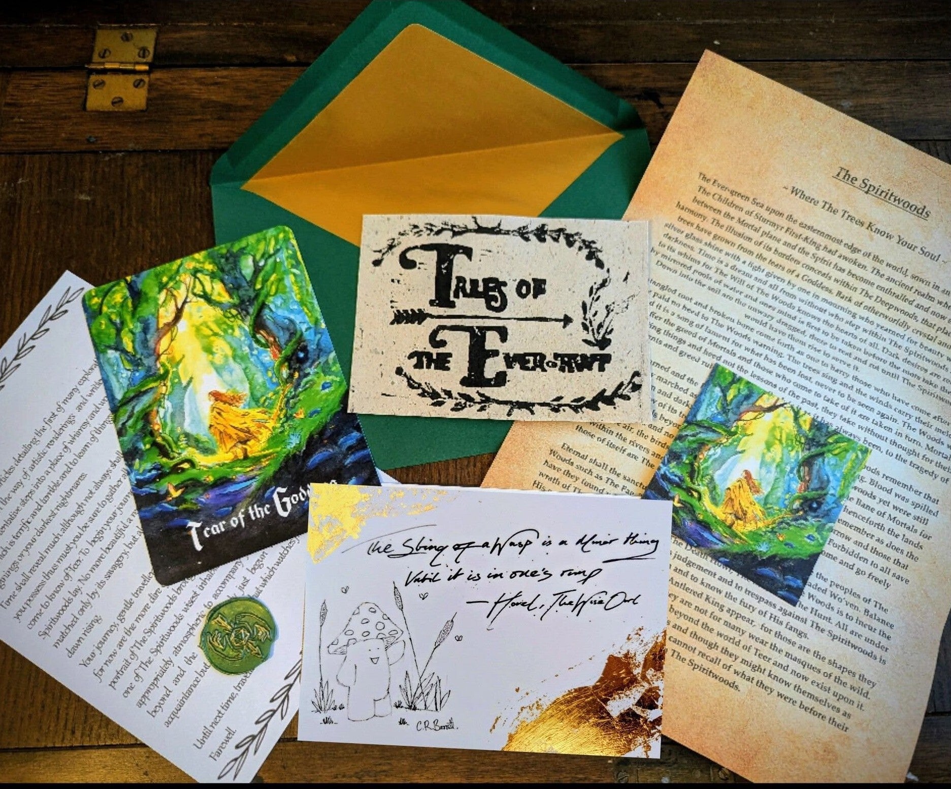 A wooden table displaying contents from our mail club, Tales of The Ever-Awt. A Quill and ink, parchment, vintage paper, illustrations, other worldly, fantasy land, antique paper goods and illustrations 