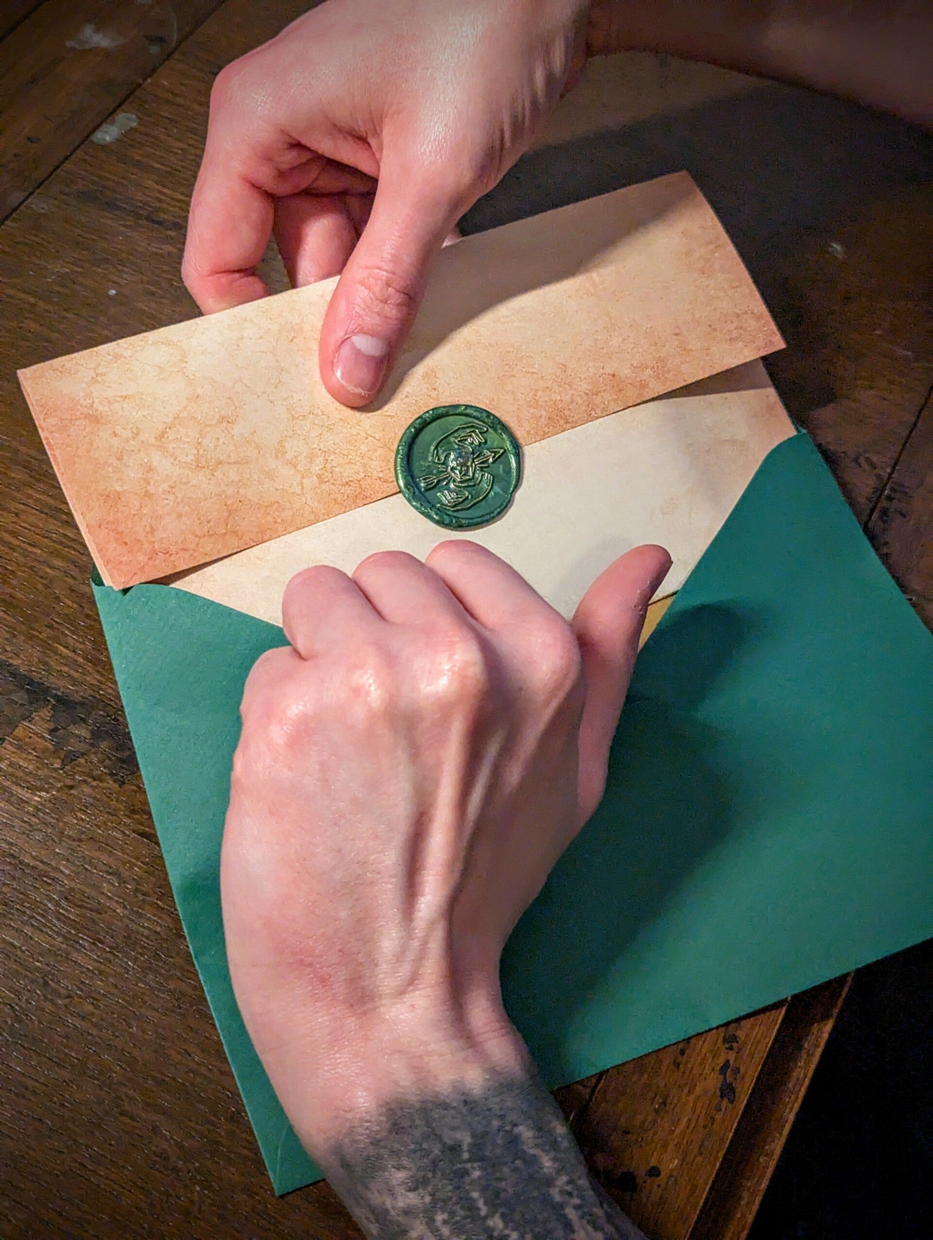 A neatly folded vintage letter sealed with wax being pulled out of an emerald green envelope. Containing contents from Tales of The Ever-Awt Mail Club 