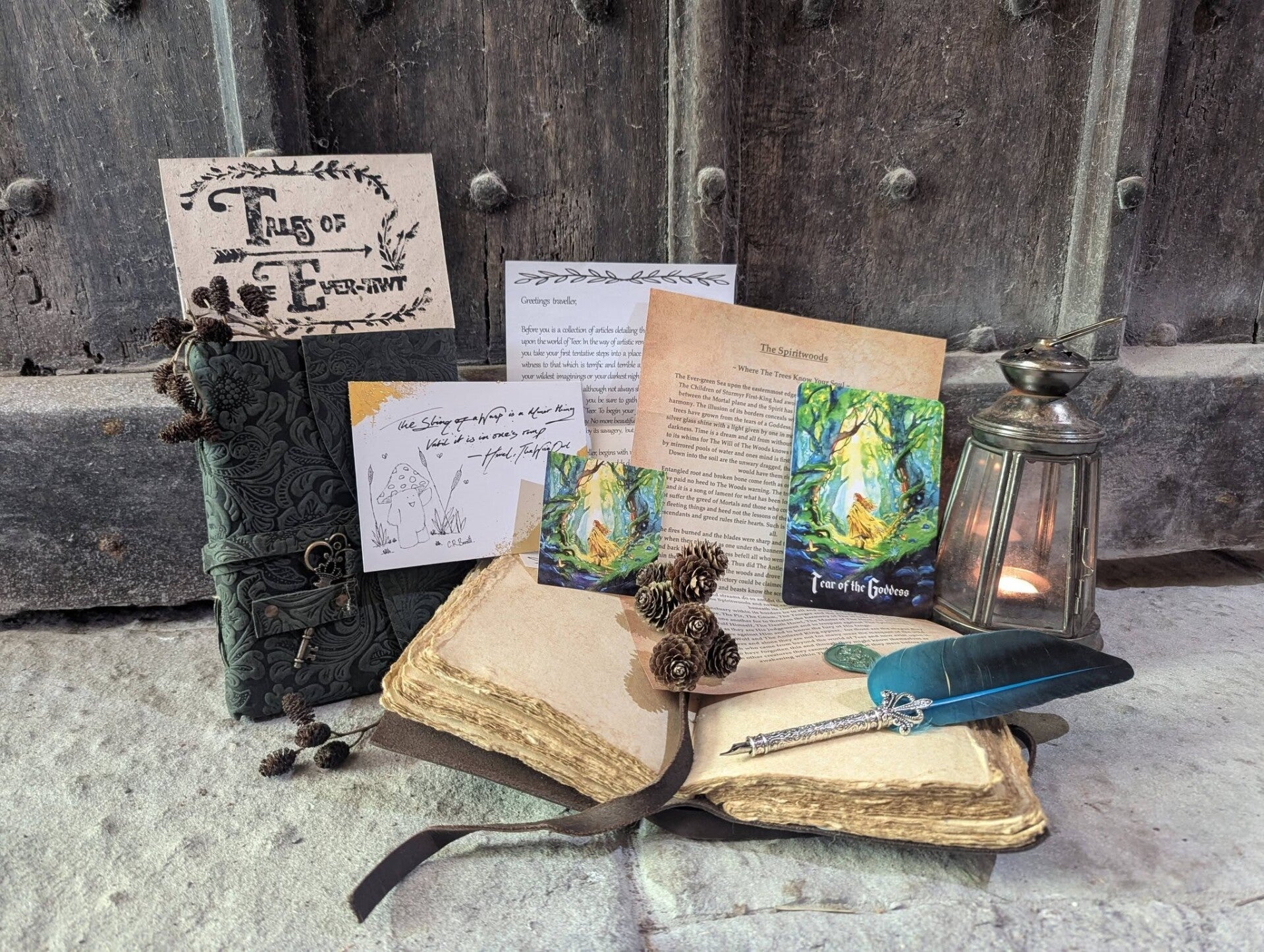 A wooden table displaying contents from our mail club, Tales of The Ever-Awt. A Quill and ink, parchment, vintage paper, illustrations, other worldly, fantasy land, antique paper goods and illustrations 