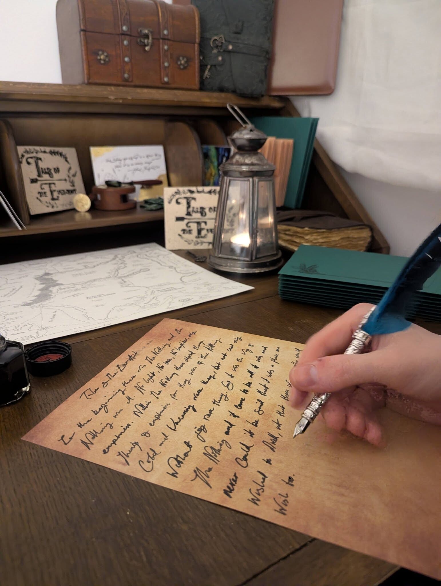 A wooden table displaying contents from our mail club, Tales of The Ever-Awt. A Quill and ink, parchment, vintage paper, illustrations, other worldly, fantasy land, antique paper goods and illustrations 