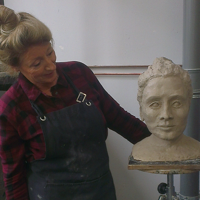 Jeanette Olyhoek standing with a sculpture of a bust of a woman she had made