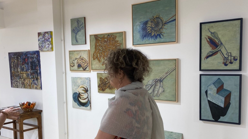 Artist Adele du Plessis walks past a number of her egg tempera paintings depicting small everyday objects enlarged and framed at Gallery Sorelle Sciarone