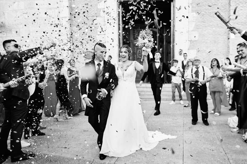 Fotografía artística de boda en blanco y negro en Madrid, pareja mirándose con emoción ante un mural religioso – por Chiriac Bogdan.