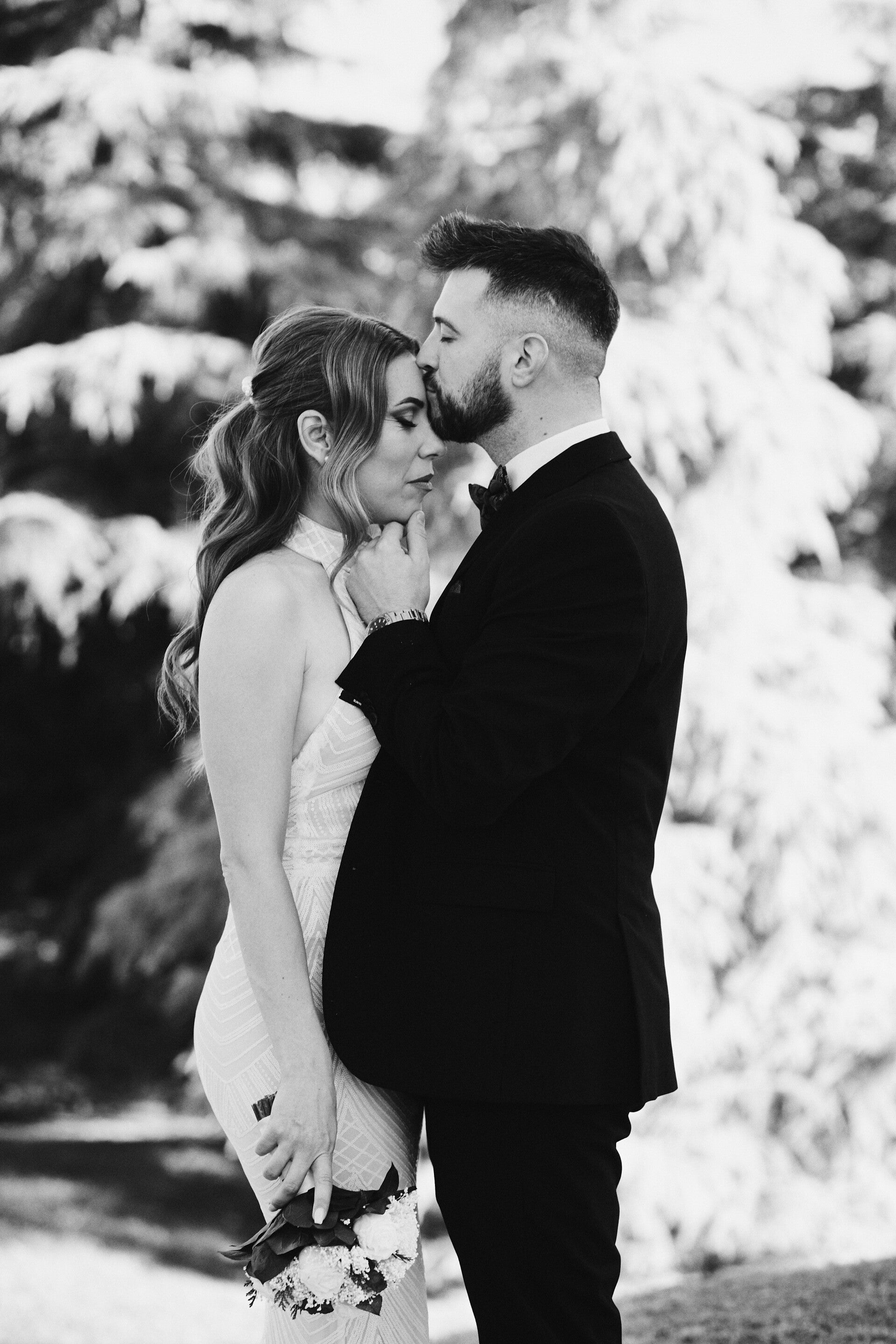 Fotografía artística de boda en blanco y negro en Madrid, pareja mirándose con emoción ante un mural religioso – por Chiriac Bogdan.