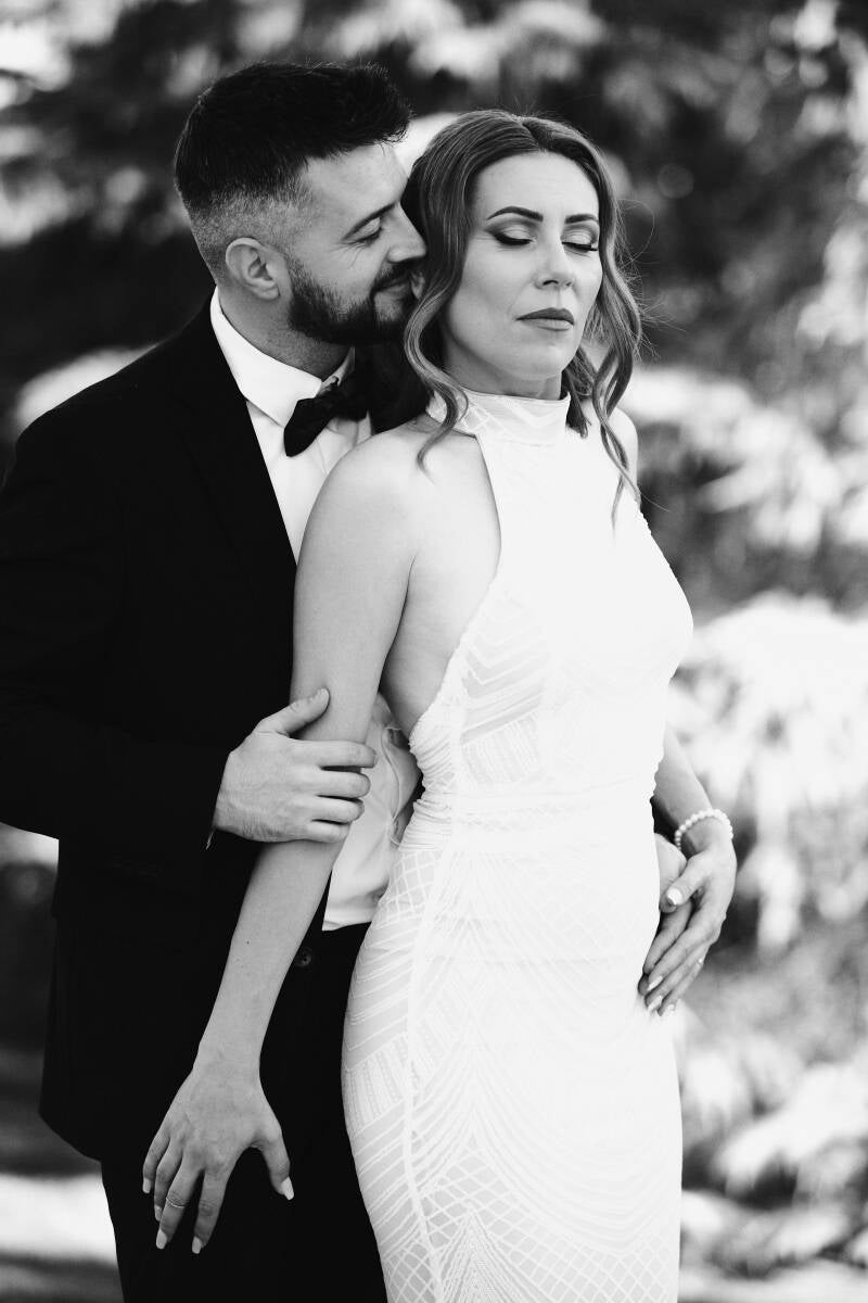 Fotografía artística de boda en blanco y negro en Madrid, pareja mirándose con emoción ante un mural religioso – por Chiriac Bogdan.