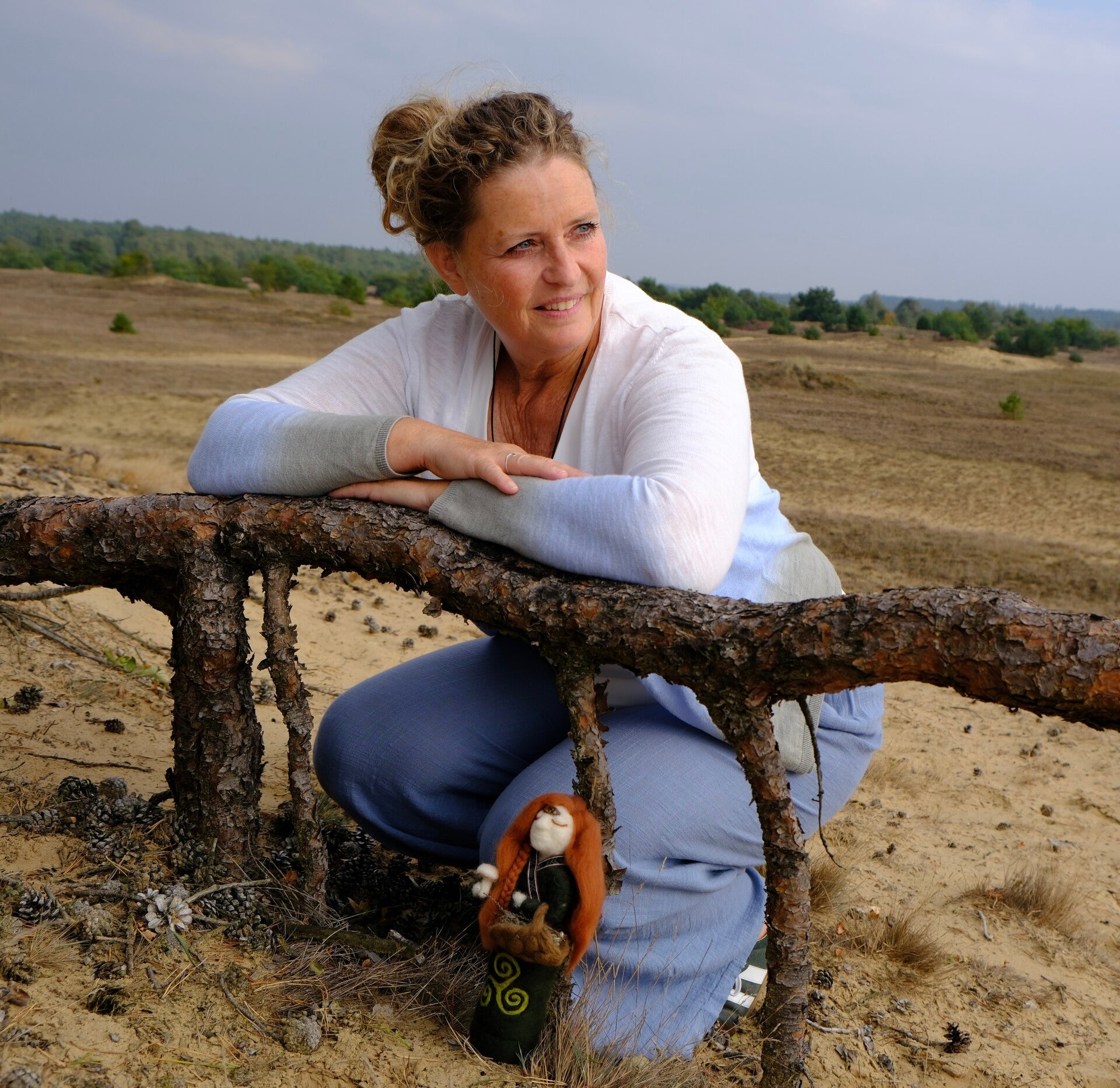 Mariëlle Postma, coach voor zorgprofessionals en kunstenaar, met een van haar medicine dolls in de natuur.