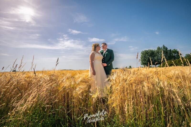 Spontane trouwfoto van bruidspaar in een goudgeel graanveld in de regio Zwevegem en Avelgem - Promofoto WoWWoW huwelijksfotografie