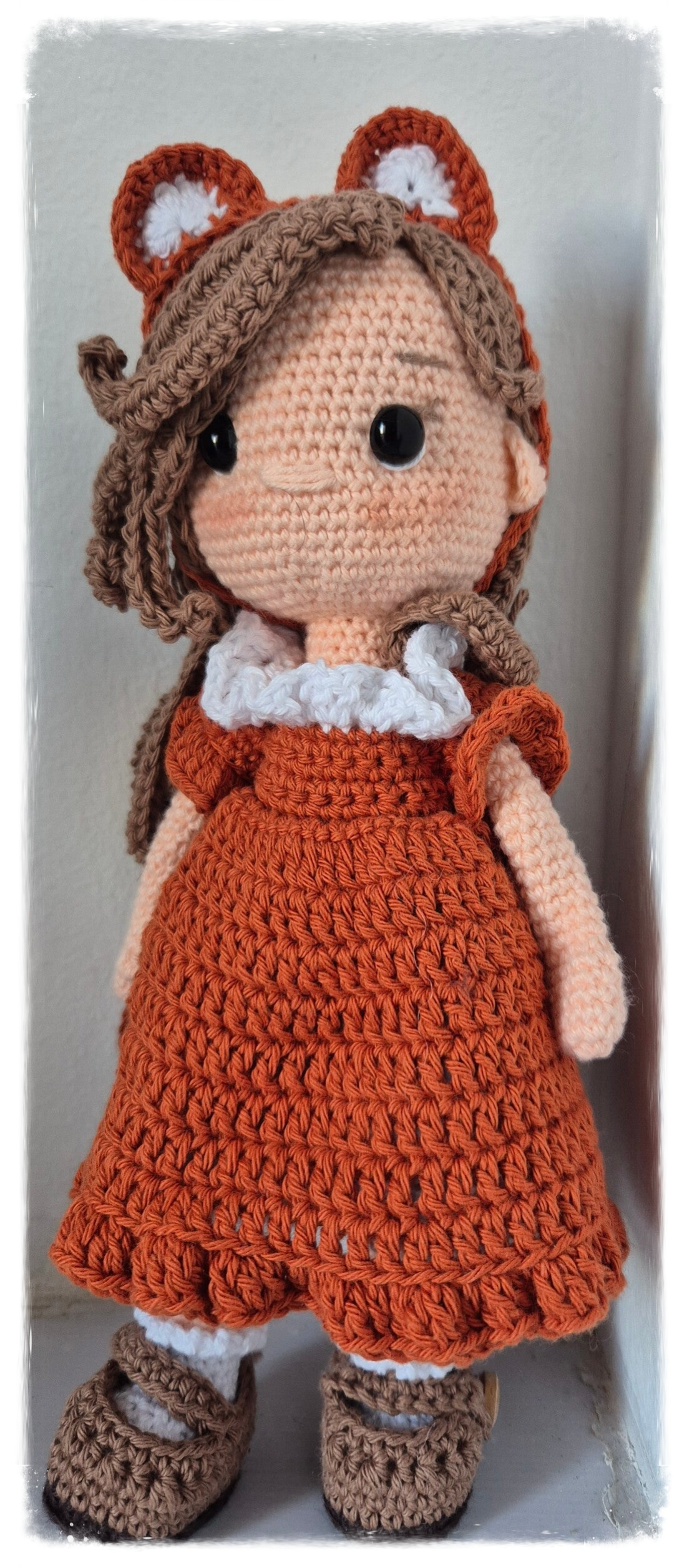 Muñeca amigurumi artesanal con vestido naranja tejida a mano.