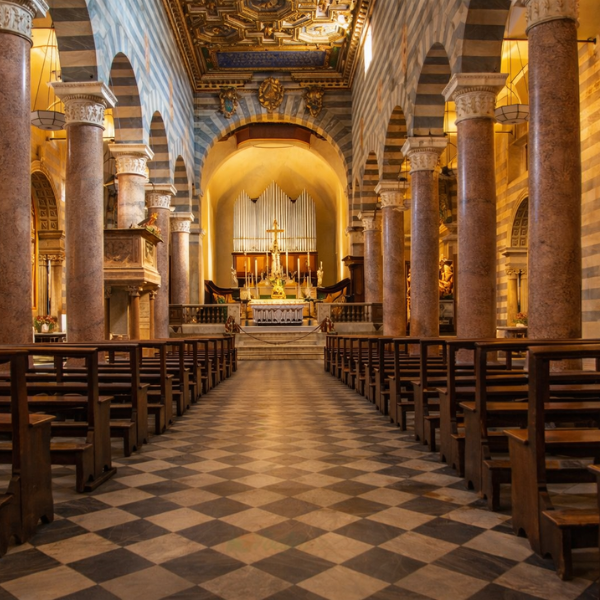 Interior of the Cathedral of Santa Maria Assunta in Volterra, with striped columns and a vaulted ceiling. (AI)