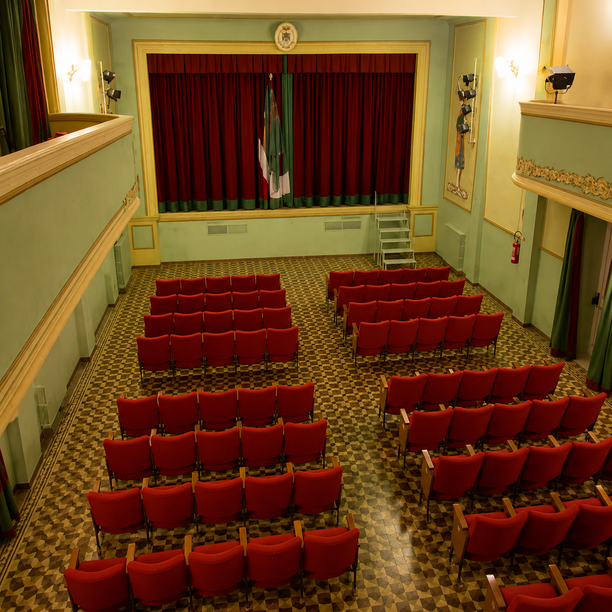 Interior of the Teatro Comunale di Lajatico with its traditional stage and rows of red theatre seats.