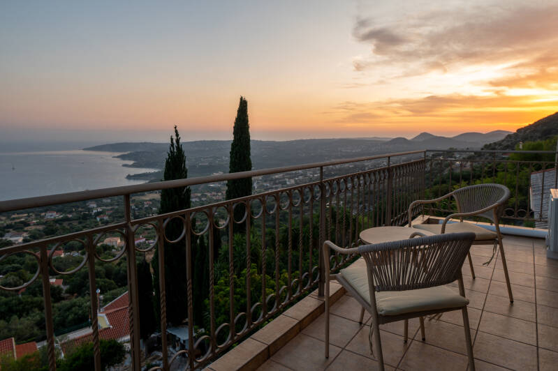 Sunset over the Ionian Sea from villa balcony in Vlachata, Kefalonia, with outdoor seating.