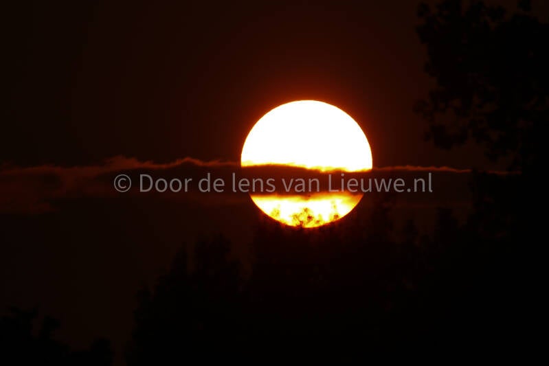 zonsondergang met wolk voor de zon