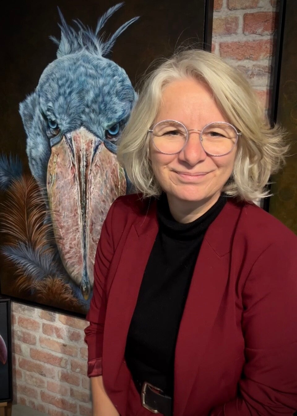 Nederlandse kunstenares, Gerrie Mathijssen tussen haar olieverfschilderijen. dieren, realalistisch vastgelegd op een schilderij