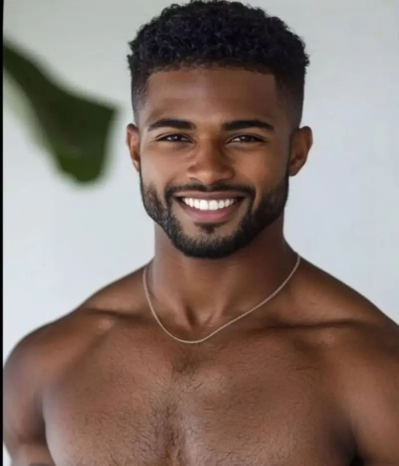 Beautiful Black man with curly hair, and trimmed beard, shirtless wearing a gold chain exuding confidence as he flahes a bold beautiful smile with perfect white teeth