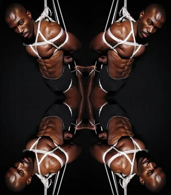 Black man tied up in a submissive position, exploring erotic power dynamics and sacred devotion rituals with a dominant partner—embodying trust, restraint, and masculine vulnerability.