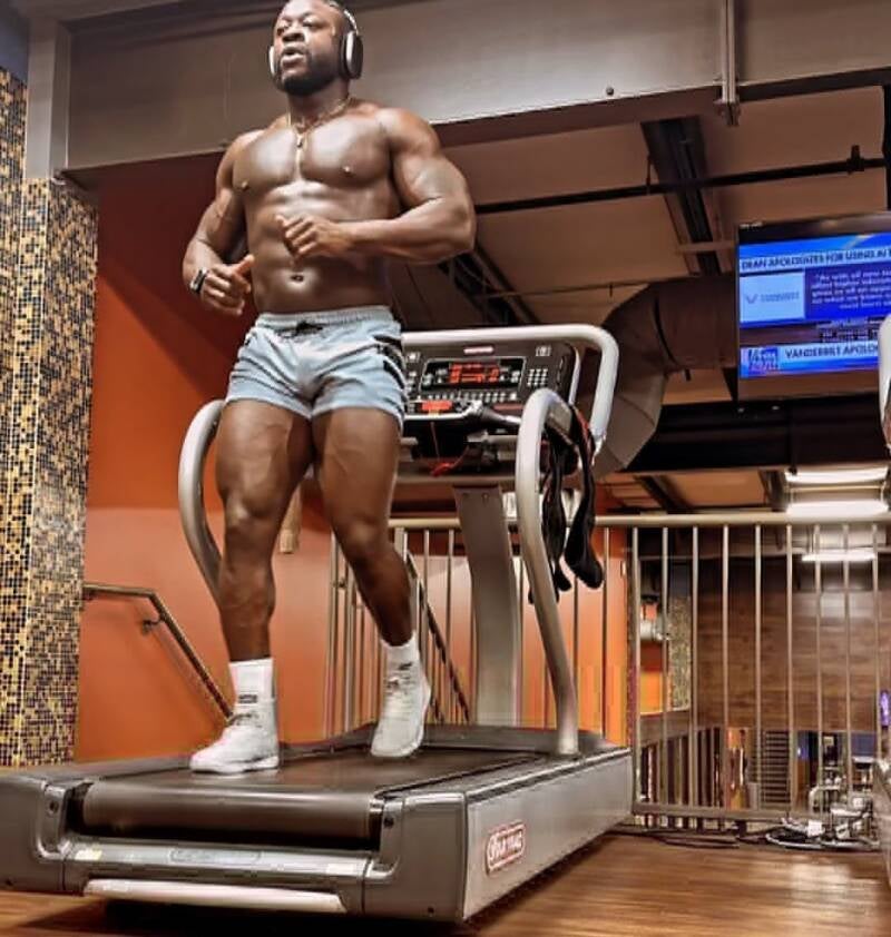 Muscular man with headphones jogging on a treadmill at the gym for his fitness workout.