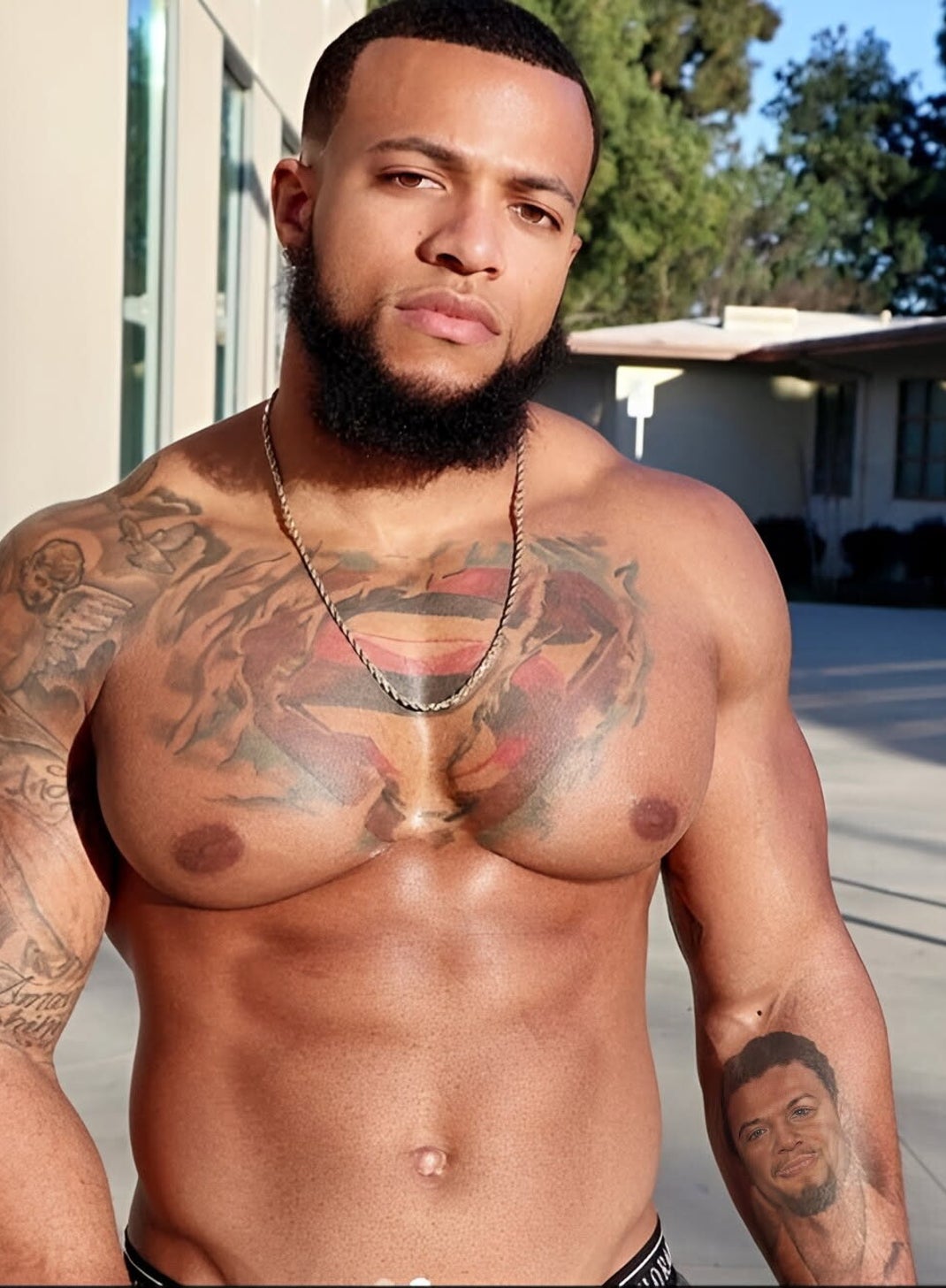 Beautiful masculine Black man with tattoos, beard, and wavy hair. Showing off muscular physique, and exuding sex appeal as he smerks up close on camera.