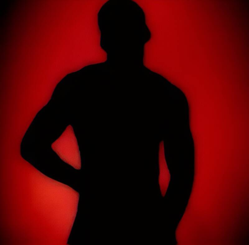 sensual silhouette of a Black man rubbing his chest behind a red glowing light