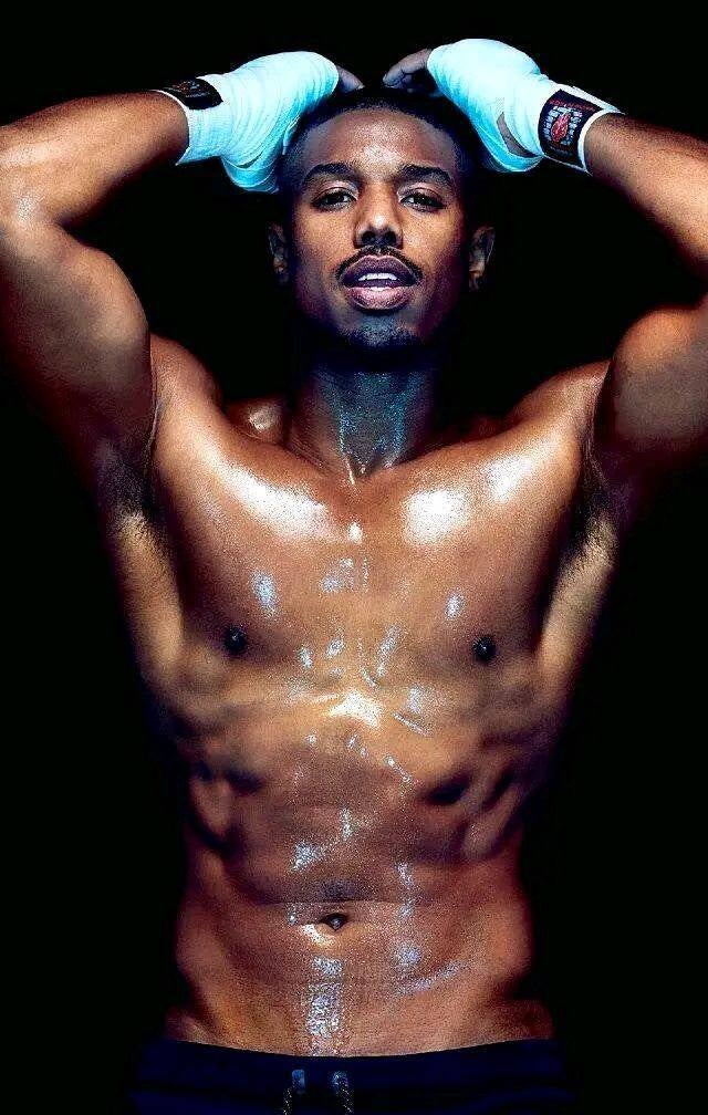 Michael B. Jordan, shirtless and sweaty, with boxing hand wraps, showcasing muscular physique and power dynamics of bdsm and control