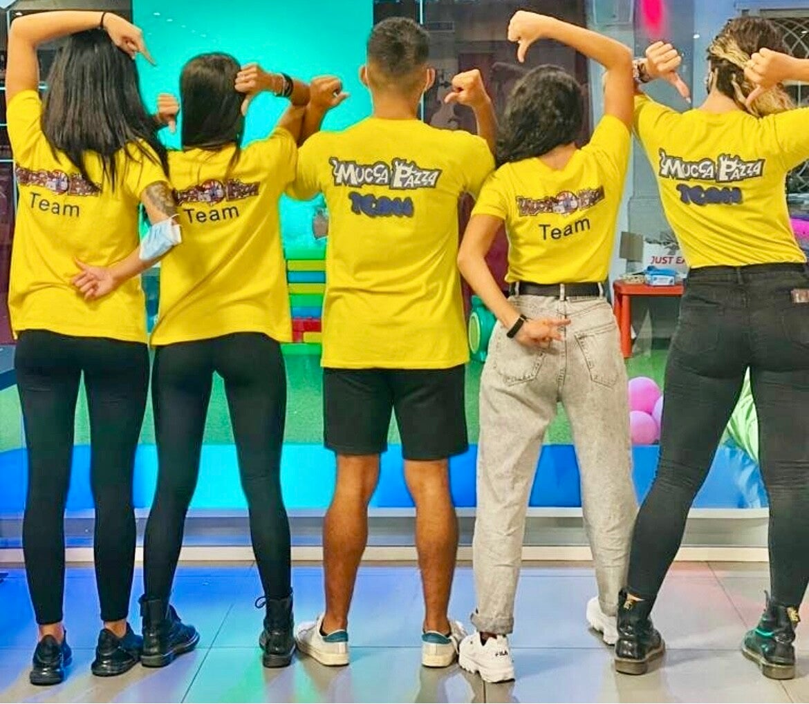 team animatori in una foto di spalle che indicano il logo del locale sulle magliette