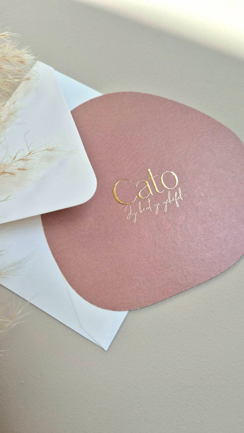 Dit net niet ronde geboortekaartje heeft prachtige oud roze kleur. Op de voorzijde wordt zowel de naam als de geboortedatum en-/of tekst gedrukt in goudfolie.  Door zijn bijzondere vorm past hij helemaal in de trend van nu. Zowel de kleur van het kaartje,