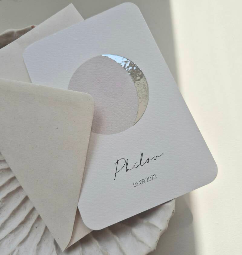 Dit prachtige kaartje weergeeft de maanstand  van de geboortedatum, hoe bijzonder ♡!  Het kaartje heeft een witte ondergrond en de maan wordt gedrukt in zilver foliedruk. De schaduwkant van de maan heeft een greige kleur. De afgeronde hoeken zijn helemaal