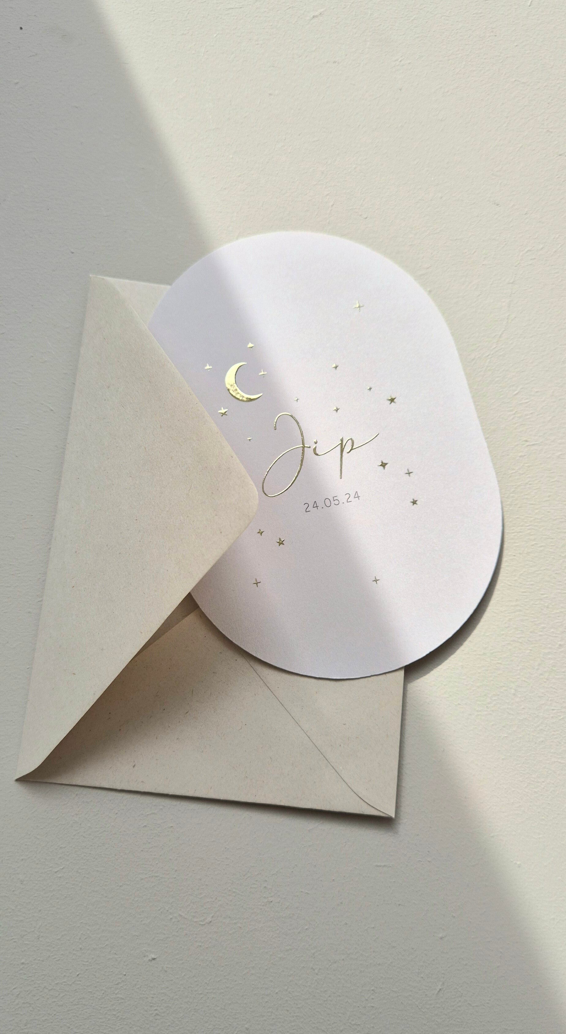 Een prachtig minimalistisch kaartje met bijzondere ovalen vorm. Het kaartje heeft een zandkleurige ondergrond met op de voorzijde een maantje, sterretjes en voornaam weergeven in goud foliedruk.  Op de achterzijde is er ruimte voor alle geboorte- en adres