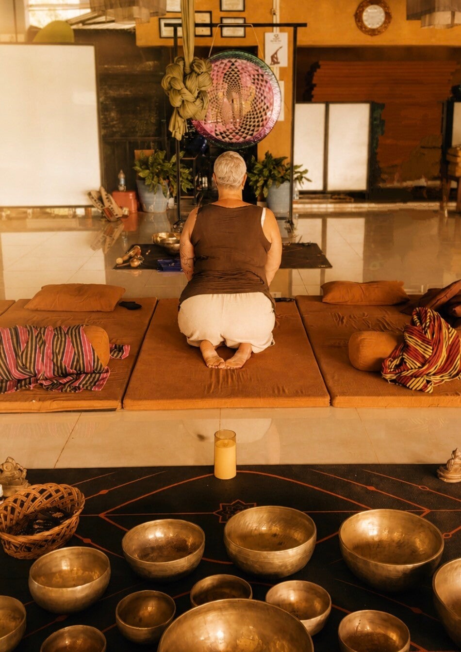 Vrouw in meditatie met klankschalen tijdens sound healing sessie, rust en balans vinden in lichaam en hoofd