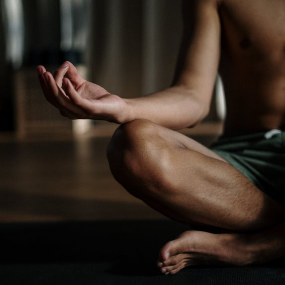 Ein Mann im Schneidersitz mit seiner rechten Hand auf dem Knie