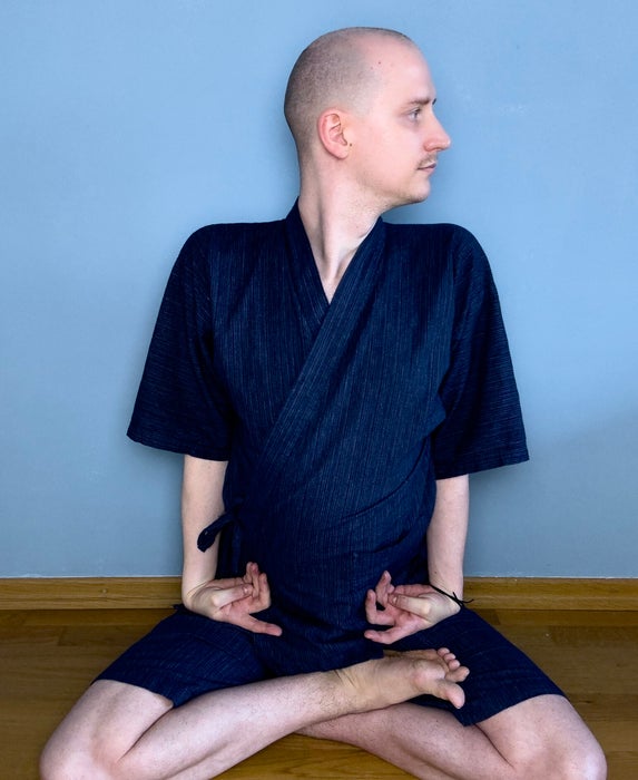 Phillip Munteanu übt tibetischen Yoga vor einer blauen Wand