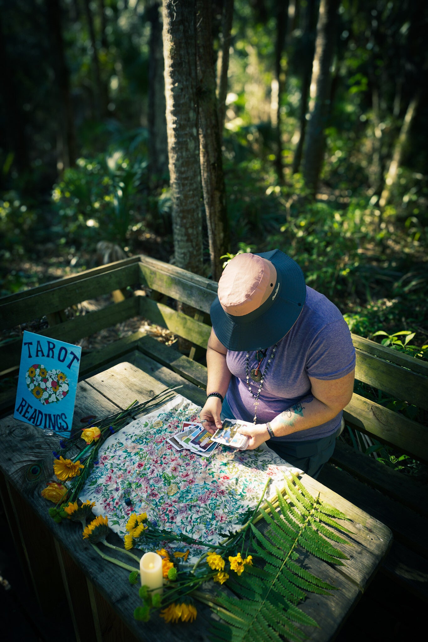 Emily, founder of Earthbound Divination, holding a fan of tarot cards outdoors.
