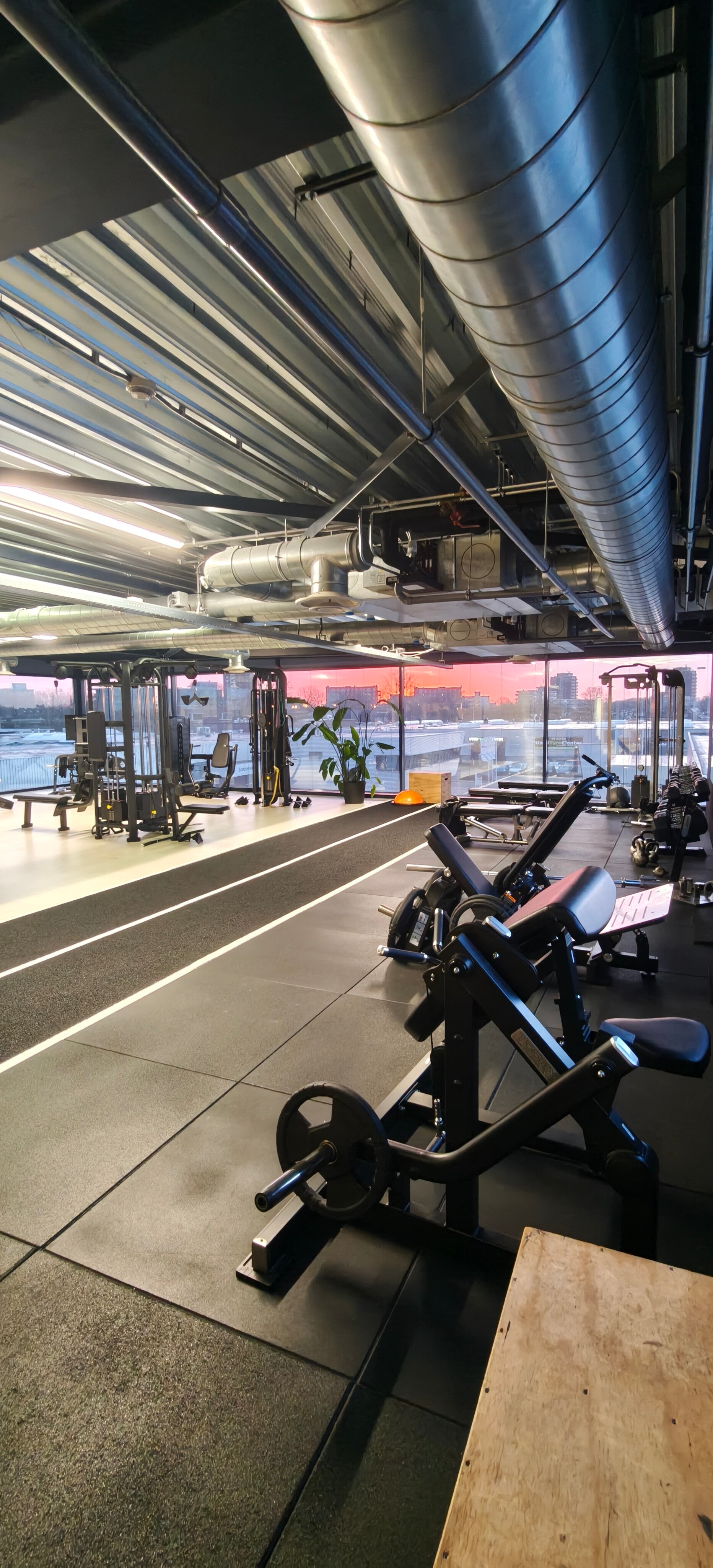 Rustige fitnessruimte bij zonsopkomst in Fit Up Leiderdorp met krachtapparatuur en vrije trainingsruimte