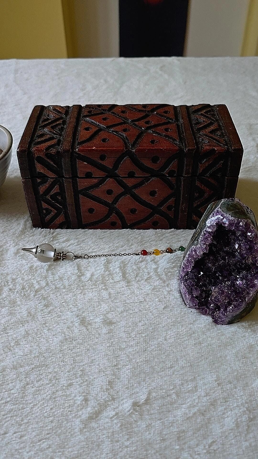 A wooden hand carved box, with an Amethyst crystal and a clear quartz  pendulum